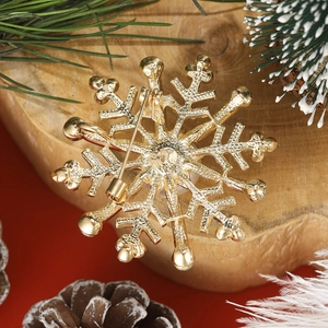 Goldene Schneeflocken-Brosche mit Nadelverschluss auf festlichem rotem Hintergrund