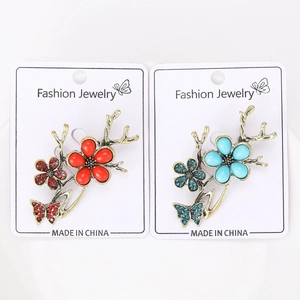 Detail view of vintage-style flower and butterfly brooches in red and blue alloy
