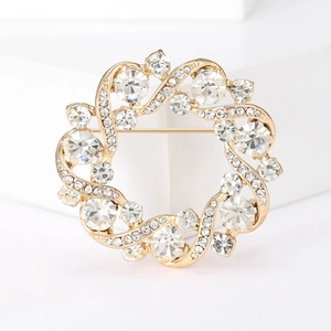 Broche couronne dorée élégante avec strass brillants pour femme sur support blanc