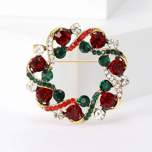 Élégante broche couronne de Noël avec strass rouges et verts sur un socle en métal doré