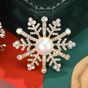 Detail einer Perlen-Schneeflocken-Brosche mit Strasssteinen auf grünem Samt-Etui