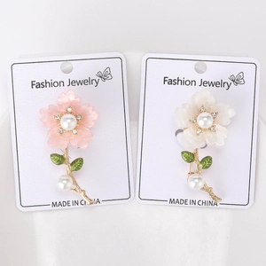 Close-up of pearl and rhinestone daisy brooches in pink and white floral designs