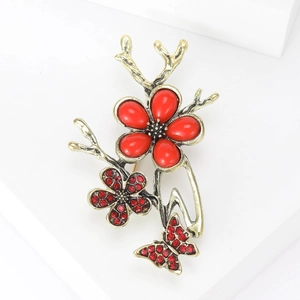 Detail view of retro gold flower butterfly brooch with red crystals and branch design