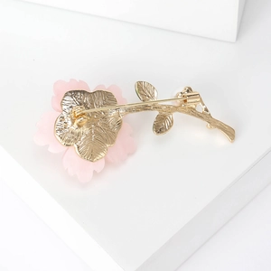 Fashionable pink daisy brooch with gold stem and pin back on white minimalist display