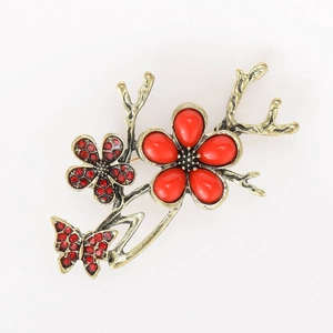 Macro shot of vintage gold butterfly and plum blossom brooch with red gemstones