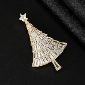 Makroaufnahme einer goldenen Weihnachtsbaum-Brosche mit Zirkonia auf schwarzem Leder