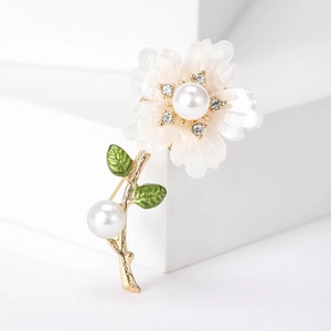 Close-up of daisy brooch with white pearls and sparkling rhinestones on gold stem