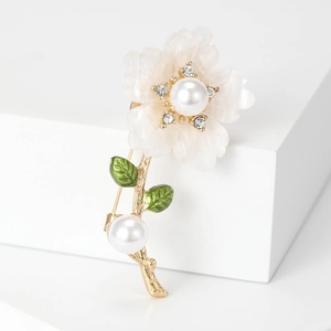 Elegant daisy flower brooch with white petals, pearls, and crystals on a gold branch