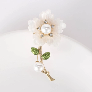 Macro shot of daisy brooch featuring white petals, gold stems, and pearl accents