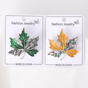 Détail de broches en forme de feuille d'érable en émail vert et orange avec strass