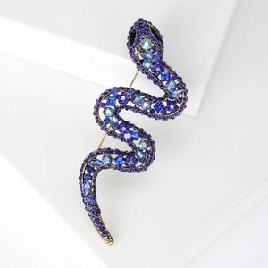 Macro view of blue crystal serpent brooch with gold finish and detailed stone inlay