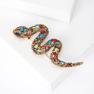 Close-up of vintage gold snake brooch with colorful rhinestones on white stand