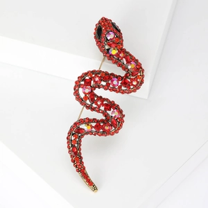 Macro shot of an S-shaped snake brooch with vibrant red rhinestones on a white geometric block