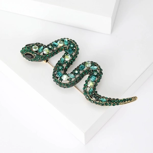 Detailed view of snake brooch with green crystals and rhinestones on gold alloy base
