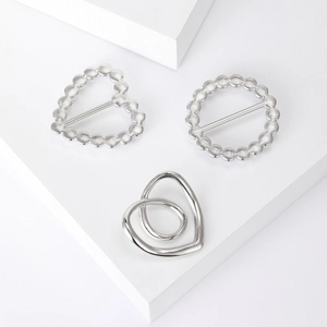 Detail of silver heart and round scarf clips with elegant embossed polka dot edges