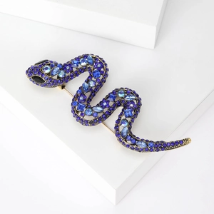 Detail of snake brooch with blue rhinestones and gold alloy on a geometric stand