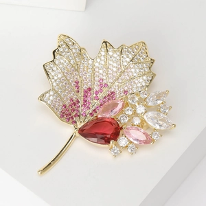 Detailed macro view of maple leaf brooch with zircon pavé and red pear-shaped gemstone