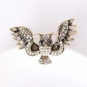 Macro shot of owl brooch with vintage gold alloy finish and iridescent rhinestones