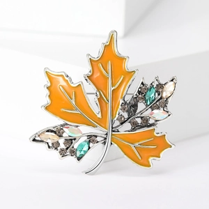 Détail de la broche feuille d'érable en émail orange et cristaux colorés sur fond blanc