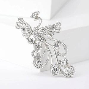 Macro shot of silver phoenix brooch with detailed rhinestone pavé wings and long tail