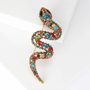 Vintage gold snake brooch with colorful rhinestones on a white geometric stone
