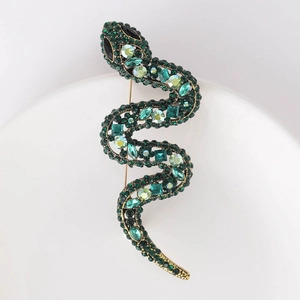 Detailed macro view of gold-tone snake brooch with green crystals and rhinestones