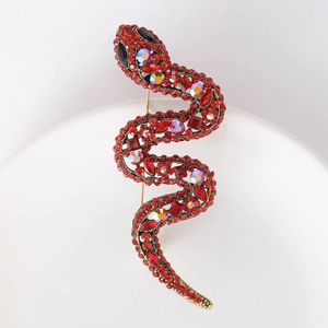Macro shot of S-shaped snake brooch with red crystals and vintage gold plating