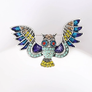Detailed macro view of an owl brooch featuring multi-colored rhinestones and silver metal finish