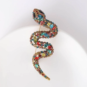 Detail view of a vintage gold snake brooch with vibrant multi-color rhinestones in S-shape
