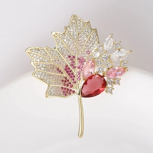 Macro detail of golden maple leaf brooch with pink cubic zirconia and red crystal gems