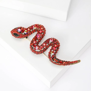 Macro shot of a red rhinestone snake brooch with dark gold metal base on white cubes
