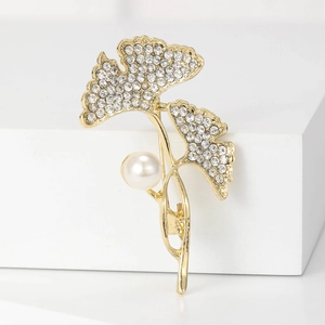 Elegante gouden ginkgo blad broche met fonkelende kristallen en een grote parel