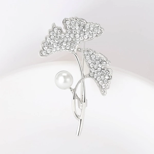 Detail van de zilveren ginkgobladspeld met fonkelende kristallen en een witte parel