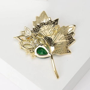 Golden maple leaf brooch with green zircon inlay and honeycomb hollow metal design