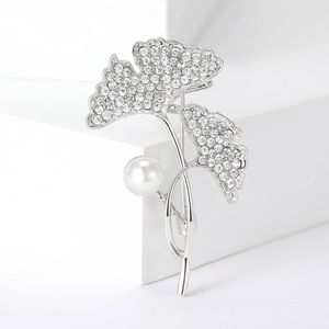 Detail van zilveren ginkgoblad broche met fonkelende kristallen en een grote witte parel