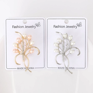 Dettaglio di eleganti spille a fiore in oro e argento con perle e strass lucidi