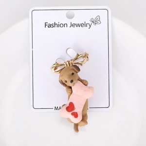 Detail of cute brown puppy brooch with pink heart bone on white ceramic display plate