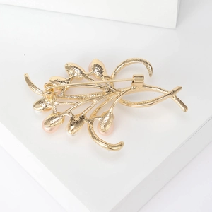 Elegante spilla a fiore dorata con perla rosa che mostra la chiusura sul retro