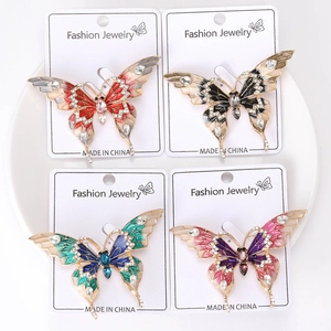 Détail de quatre broches papillons en émail avec strass sur une carte à bijoux