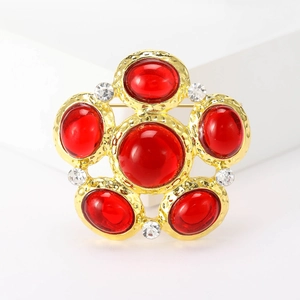 Macro detail of red gemstone flower brooch with textured gold plating and crystals