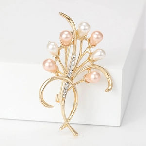 Elegante spilla a fiore dorata con perle e strass su un supporto espositivo bianco