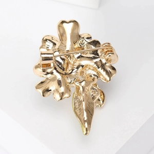 Broche fleur et coccinelle dorée montrant le mécanisme de l'épingle au dos du bijou