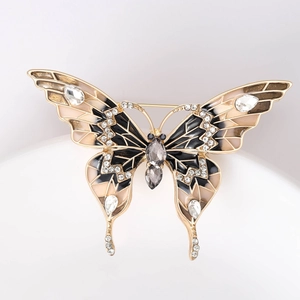 Détail d'une broche papillon dorée avec ailes en émail et cristaux scintillants