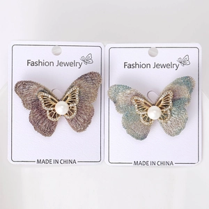 Détail d'une broche papillon avec strass et perle sur une carte de présentation bijoux
