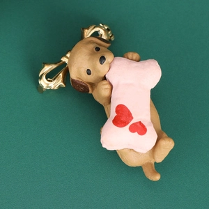 Close-up of cute brown dog brooch with pink bone and golden metal bow clasp