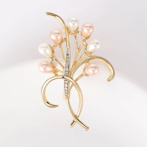 Dettaglio di elegante spilla floreale dorata con perle sintetiche e strass luccicanti