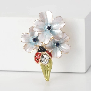Broche fleur et coccinelle élégante avec pétales émaillés bleus et strass brillants