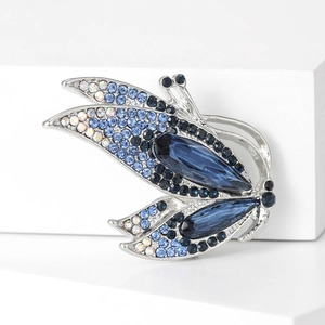 Élégante broche papillon avec cristaux bleus sur un support géométrique blanc pur