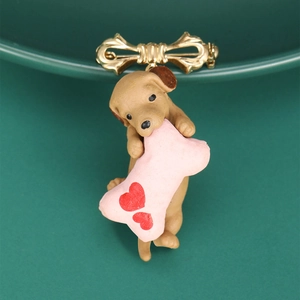 Detailed close-up of a brown puppy brooch with pink bone and golden metal bow clasp