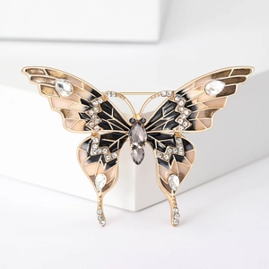 Détails de la broche papillon avec ailes émaillées et strass brillants sur fond blanc